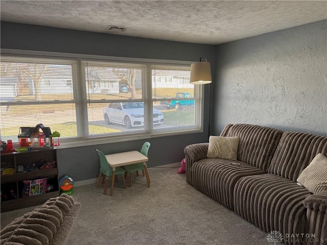 playroom with a wealth of natural light, a textured ceiling, and carpet flooring