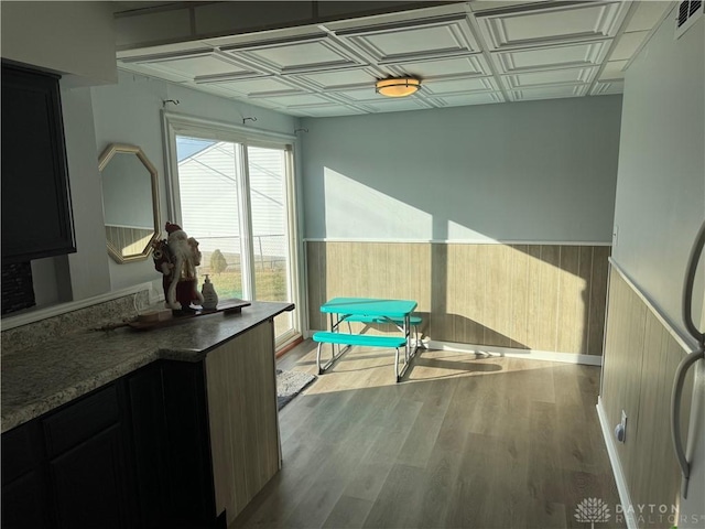 interior space with a wainscoted wall, visible vents, wood finished floors, and an ornate ceiling