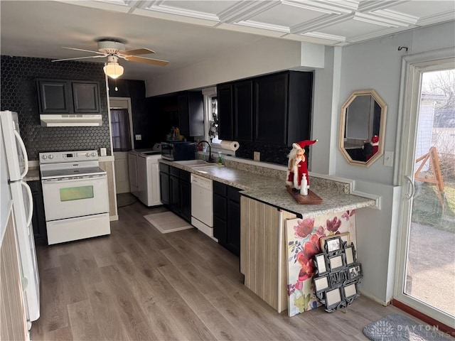 kitchen featuring white appliances, washer / dryer, light wood-style flooring, under cabinet range hood, and a sink