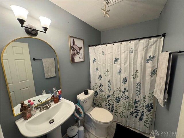 bathroom with a shower with curtain, sink, and toilet