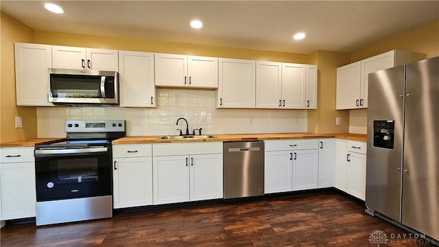 kitchen with stainless steel appliances, white cabinetry, and butcher block countertops