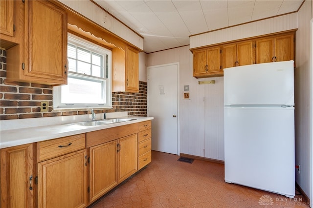 kitchen with ornamental molding, white fridge, and sink