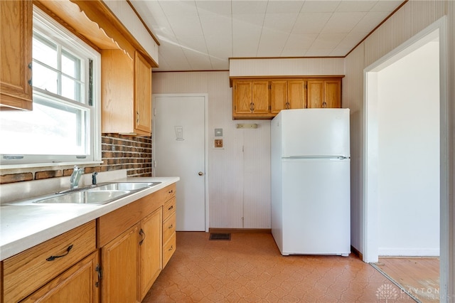 kitchen featuring sink, crown molding, and white fridge