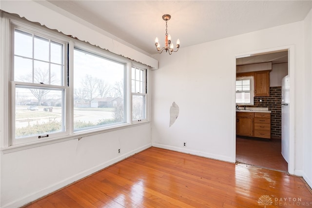 spare room with sink, a chandelier, and light hardwood / wood-style flooring