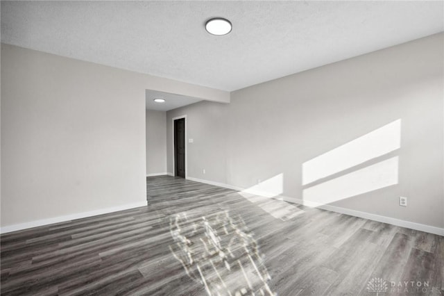 spare room with dark hardwood / wood-style floors and a textured ceiling