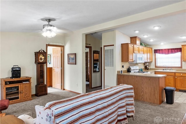 kitchen with sink, range, light carpet, kitchen peninsula, and ceiling fan