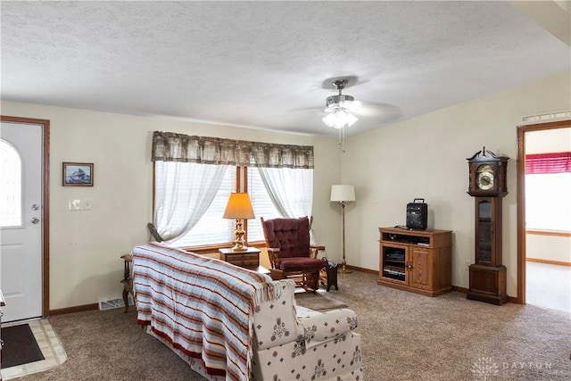 carpeted living room featuring ceiling fan and a textured ceiling