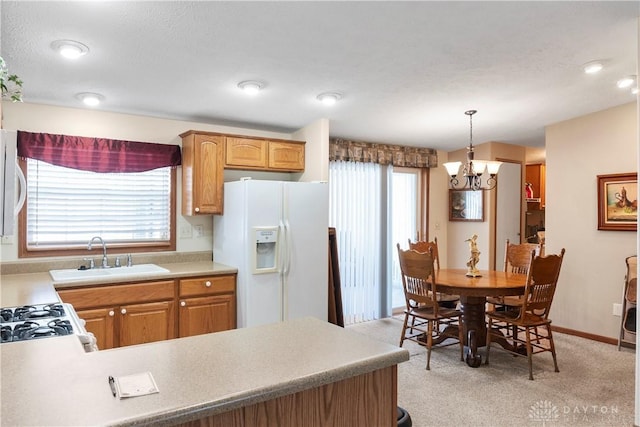 kitchen with pendant lighting, sink, white appliances, a wealth of natural light, and light colored carpet