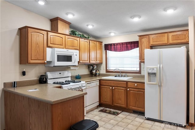 kitchen with sink, white appliances, and kitchen peninsula