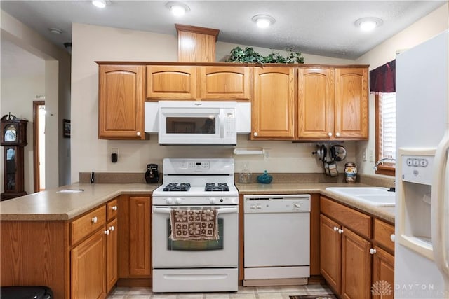 kitchen with sink, white appliances, and kitchen peninsula