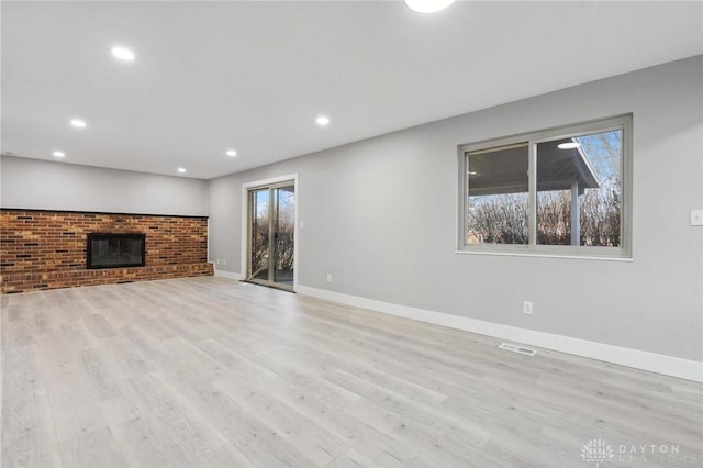 unfurnished living room featuring a brick fireplace and light wood-type flooring