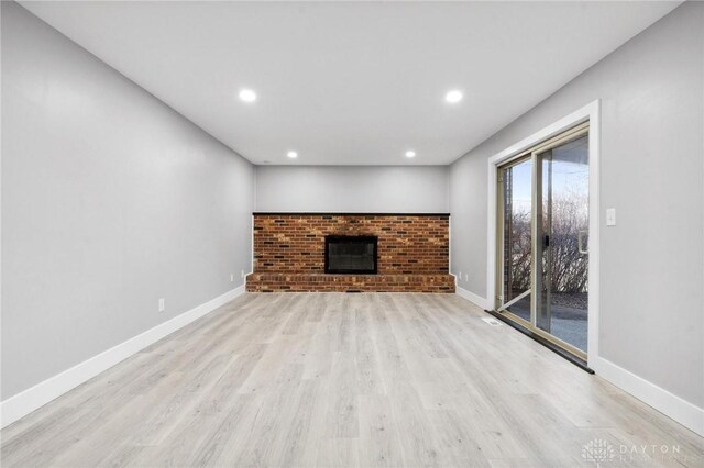 unfurnished living room featuring a brick fireplace and light wood-type flooring