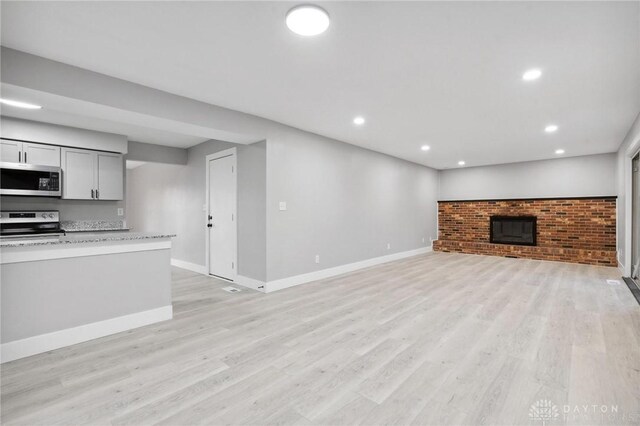 unfurnished living room featuring a brick fireplace and light hardwood / wood-style flooring