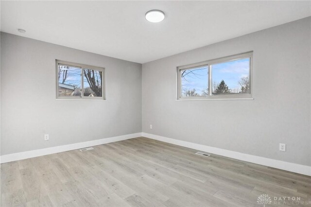 empty room with light hardwood / wood-style flooring and plenty of natural light