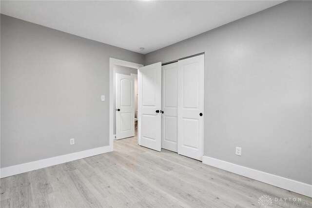 unfurnished bedroom with light wood-type flooring and a closet