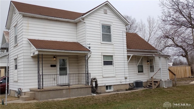 rear view of property with covered porch, a shingled roof, and a lawn