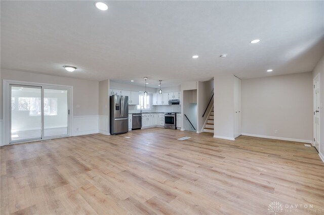 unfurnished living room with sink and light hardwood / wood-style floors