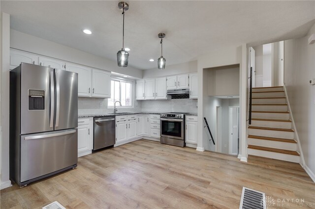 kitchen featuring sink, pendant lighting, stainless steel appliances, decorative backsplash, and white cabinets