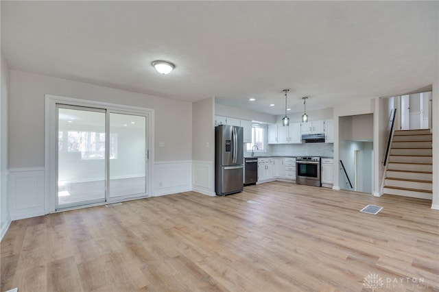 kitchen featuring sink, white cabinetry, hanging light fixtures, light hardwood / wood-style flooring, and stainless steel appliances