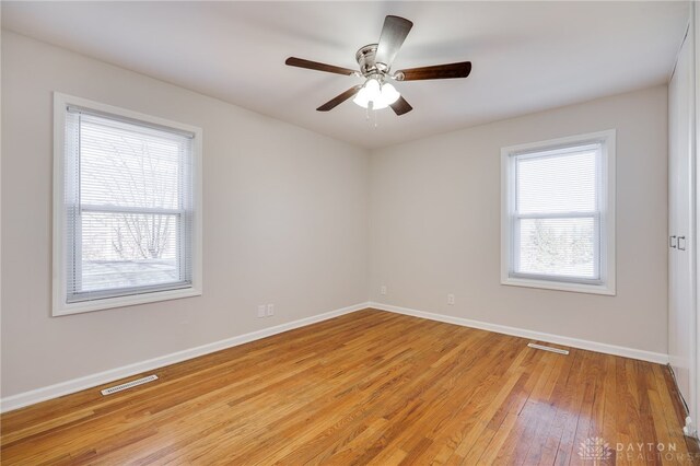 empty room featuring a wealth of natural light, light hardwood / wood-style floors, and ceiling fan