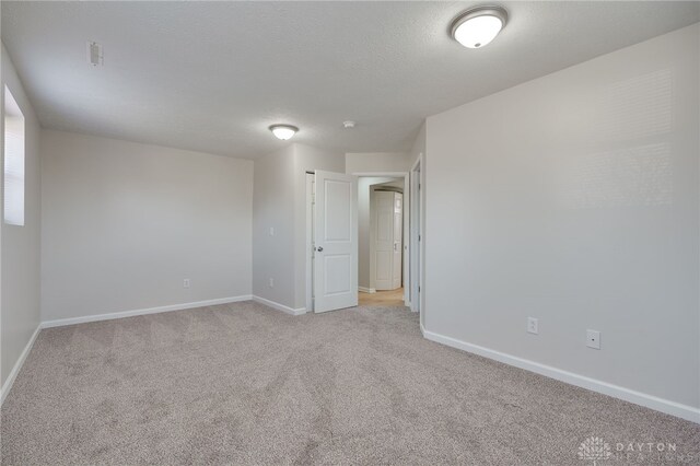 spare room featuring light carpet and a textured ceiling