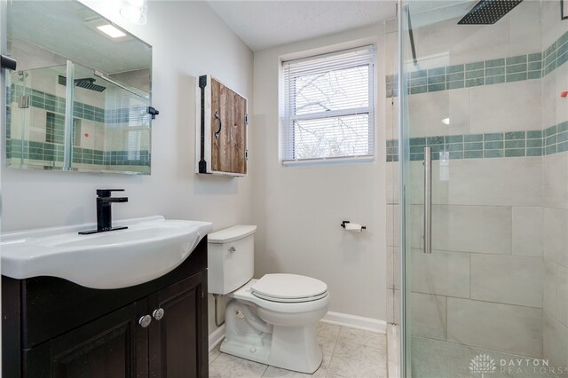 bathroom with vanity, a shower with door, and toilet