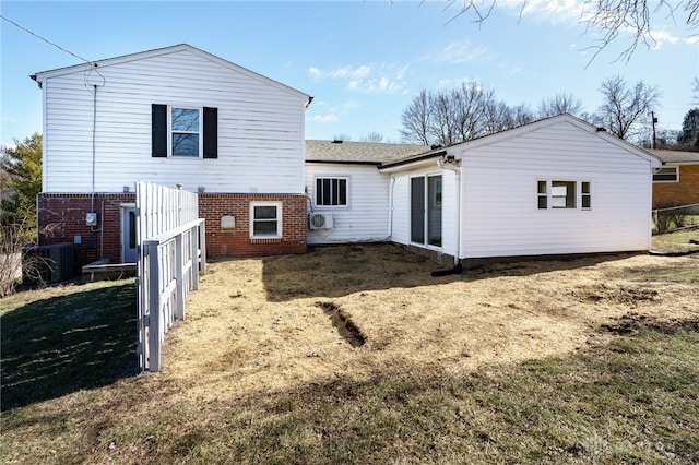 rear view of property with central AC and a lawn