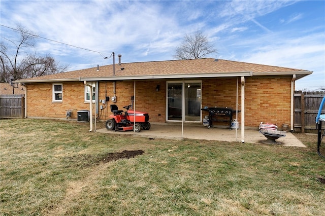 rear view of house with cooling unit, a patio, and a lawn