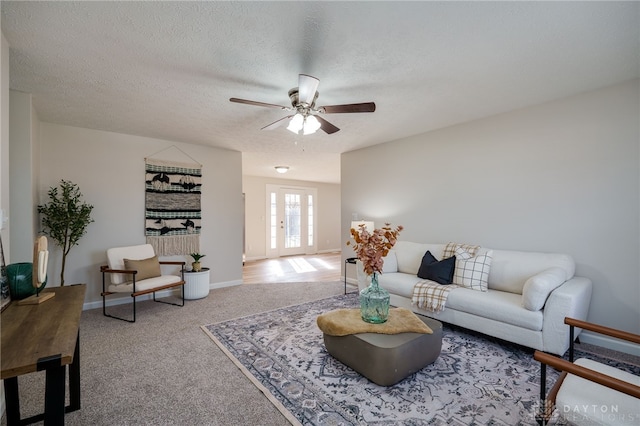 carpeted living room with french doors, ceiling fan, and a textured ceiling