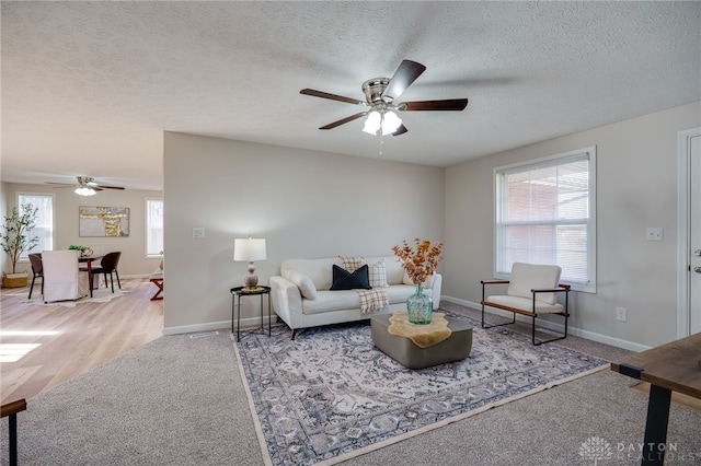 carpeted living room with ceiling fan and a textured ceiling