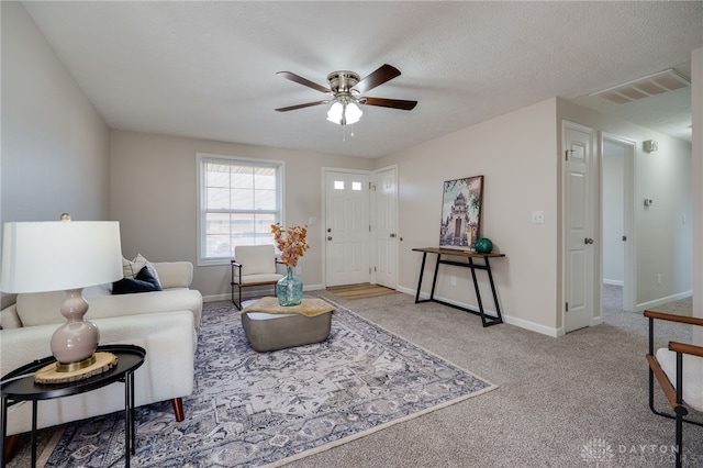 carpeted living room featuring ceiling fan and a textured ceiling