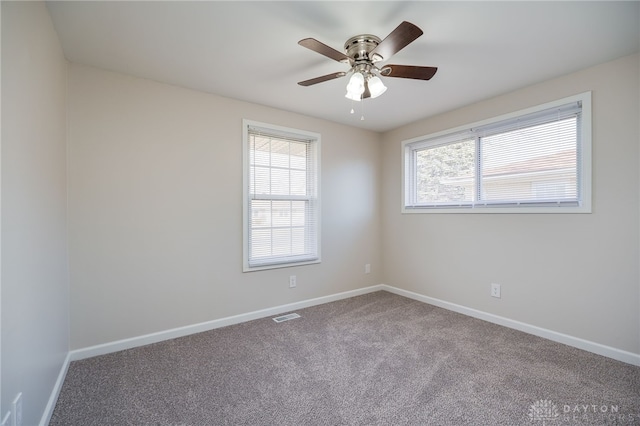 carpeted empty room featuring a wealth of natural light and ceiling fan