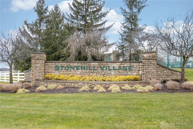 community / neighborhood sign with a lawn and fence