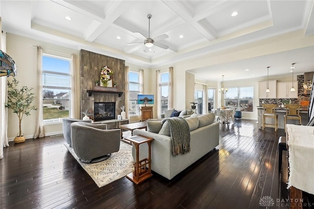 living area featuring plenty of natural light, coffered ceiling, a fireplace, and dark wood finished floors