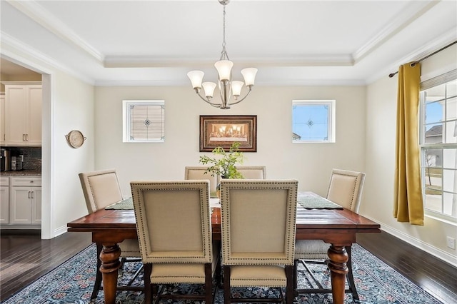 dining space featuring dark wood-style floors, a raised ceiling, a chandelier, and crown molding