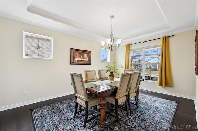 dining space featuring dark wood-style floors, ornamental molding, a raised ceiling, and baseboards