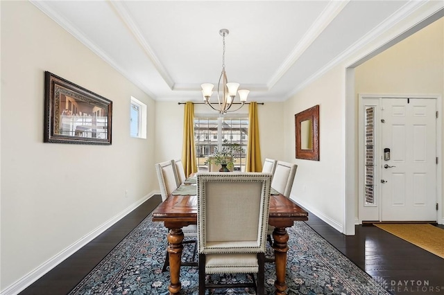 dining space with baseboards, a tray ceiling, dark wood finished floors, and a chandelier