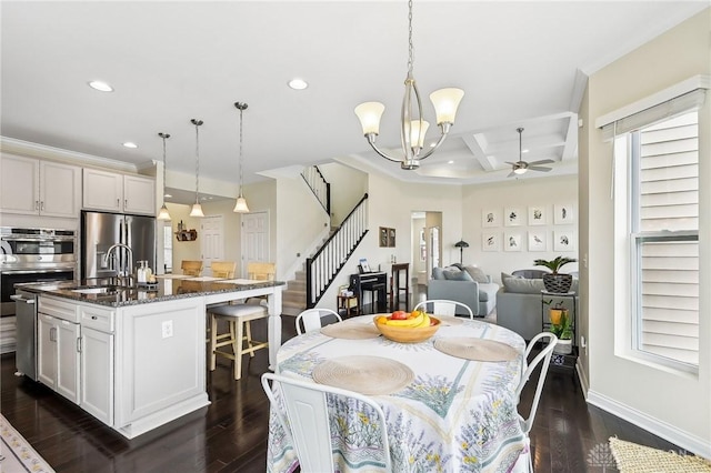 dining space featuring stairs, recessed lighting, dark wood-type flooring, coffered ceiling, and ceiling fan with notable chandelier