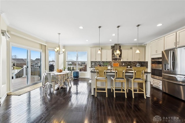 kitchen featuring appliances with stainless steel finishes, plenty of natural light, dark wood finished floors, and decorative backsplash