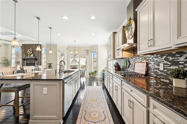 kitchen with a breakfast bar, backsplash, appliances with stainless steel finishes, a kitchen island with sink, and a sink