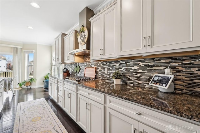 kitchen with dark stone countertops, stainless steel gas cooktop, backsplash, and dark wood-type flooring