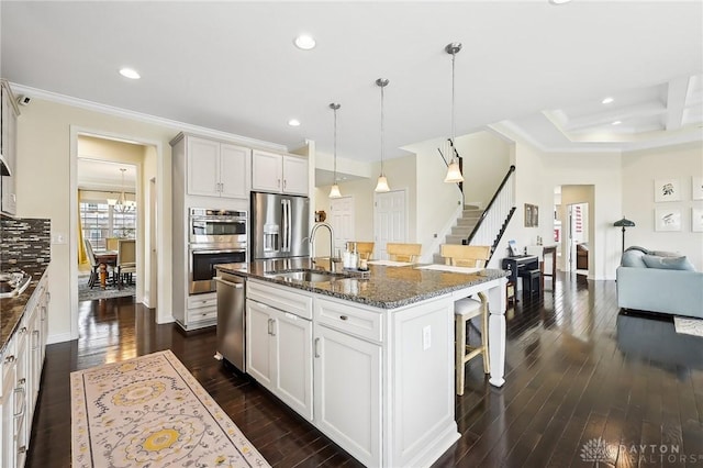 kitchen with crown molding, appliances with stainless steel finishes, dark wood-type flooring, a sink, and a kitchen breakfast bar