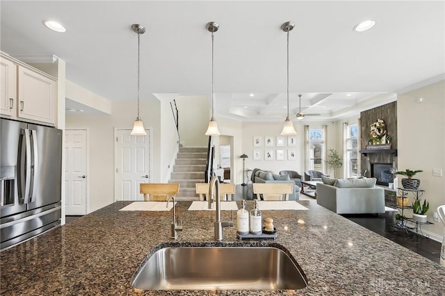 kitchen with recessed lighting, a large fireplace, a sink, hanging light fixtures, and stainless steel refrigerator with ice dispenser