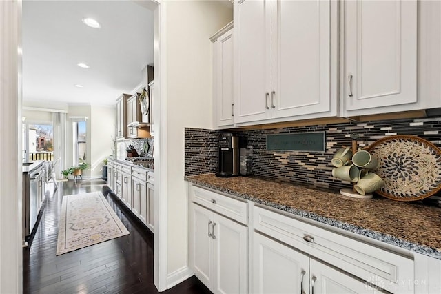 kitchen with white cabinets, dark wood finished floors, dark stone counters, and backsplash