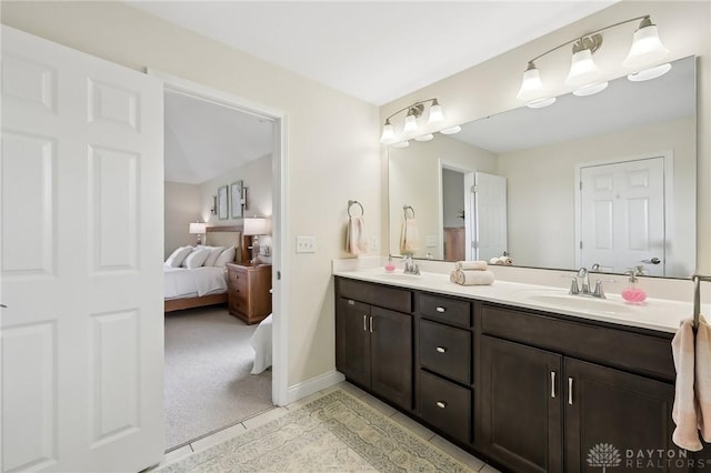 ensuite bathroom featuring double vanity, a sink, baseboards, and ensuite bathroom