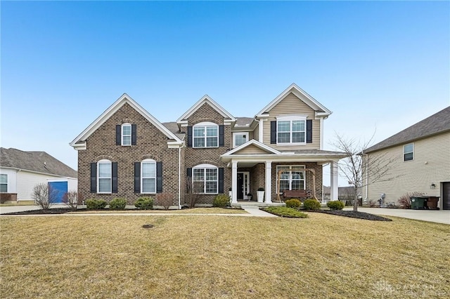 view of front of home featuring brick siding, a porch, and a front yard