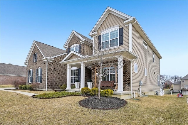 view of front of property featuring a front yard, fence, a porch, and brick siding