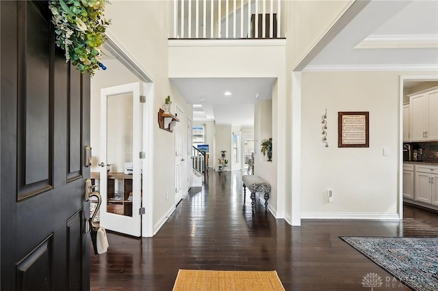 entryway featuring dark wood-style floors, a high ceiling, baseboards, and crown molding