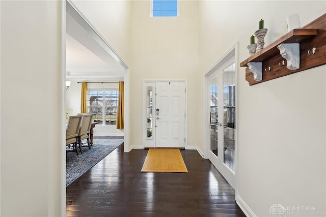 foyer entrance featuring a high ceiling, baseboards, and dark wood-type flooring