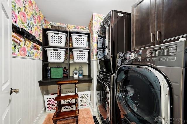 laundry area featuring stacked washing maching and dryer and cabinet space